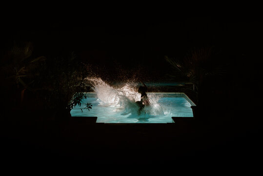 Kids jumping in an outdoor pool at night on vacation. 
