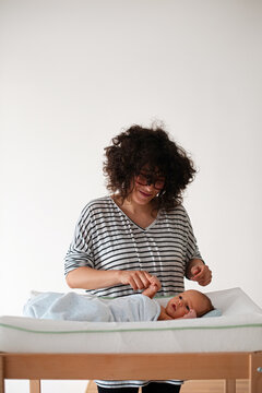 Mother Changing Newborn Baby on Nursery Changing Table
