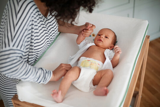 Mother Changing Newborn Baby On Changing Table