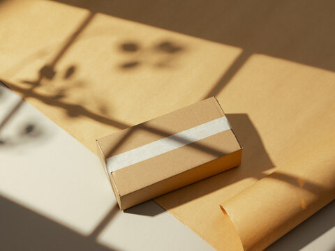 Brown cardboard box with white tape on a surface with natural light