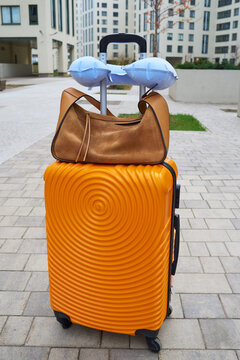 Bright orange suitcase with a stylish bag at a modern building