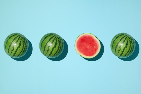 Mini watermelons on a blue background, one sliced open to reveal