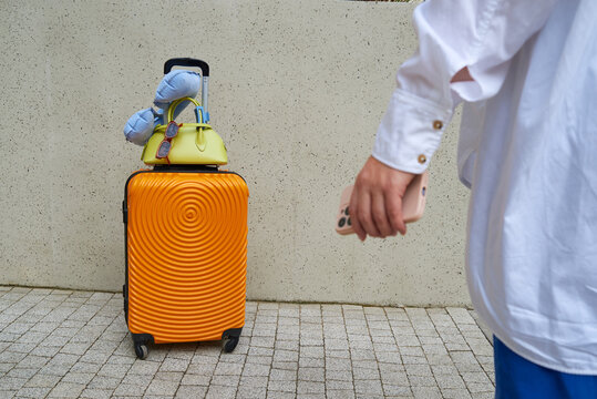 A traveler walks towards a bright orange suitcase