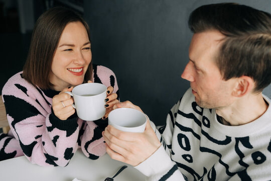 Woman happily looking at man while having tea together