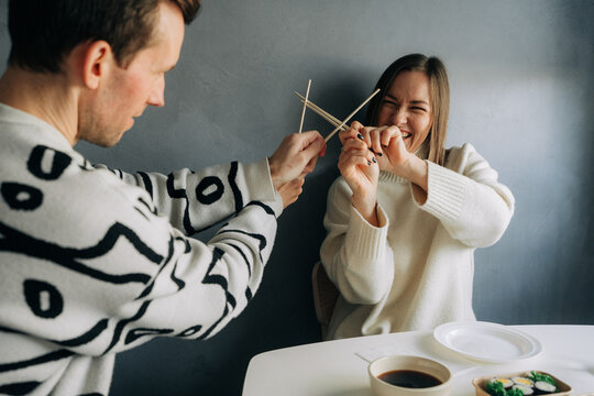 Man and woman playing with chopsticks at kitchen table