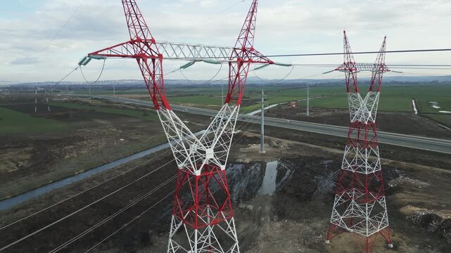 Aerial view of electricity pylon details, insulators  and lines against cloudy sky.