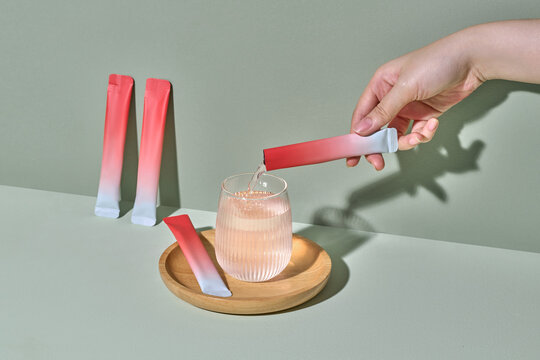Hand Pouring Instant Drink Powder Into Glass on Wooden Tray