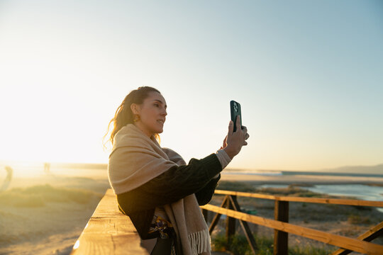 Woman Recording Video At Sunset