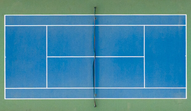 Aerial view of a blue tennis court with white boundary lines and a green surrounding surface Reggello, Tuscany, Italy.