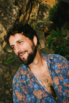 Man smiles near rocks and plants in a natural setting