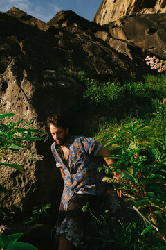 Man walking among rocks and plants in a natural setting