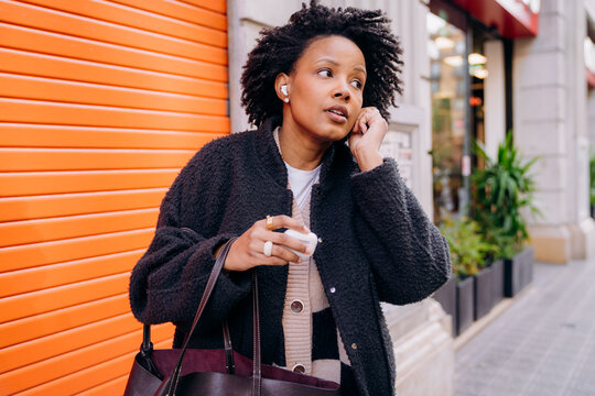 A woman putting on earbuds