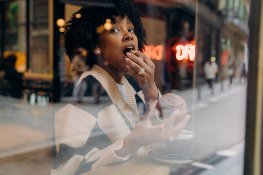 A woman eating a bun in a cafe
