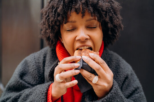 A woman eats a bun in the city