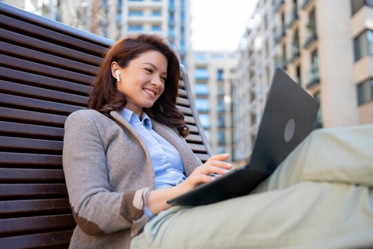 Woman works on laptop in city park setting