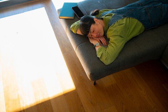 Woman resting on couch in bright room during day