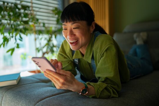 Woman using phone while relaxing at home