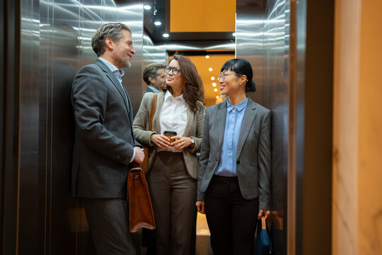 Colleagues talking together inside elevator