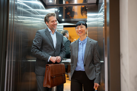 Two colleagues enter an office elevator