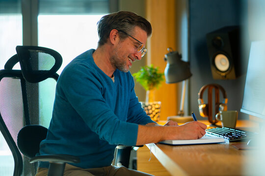 Man writes notes at desk in home office setting