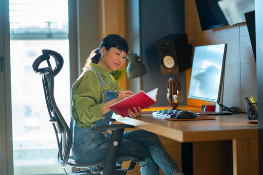 Woman writing in notebook at desk in modern office