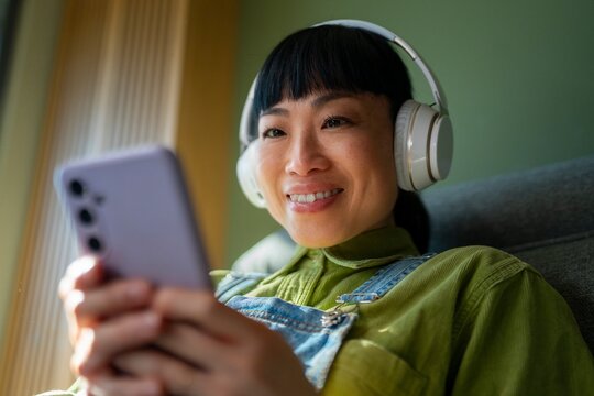 A person sits on a couch with a smartphone in hand