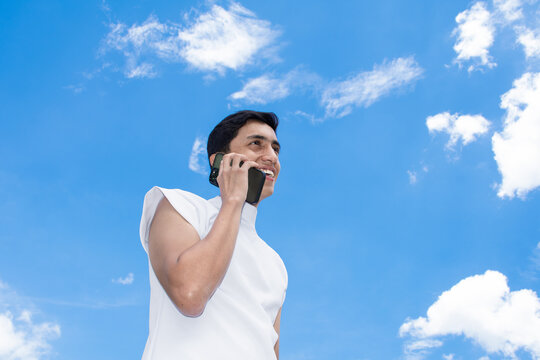 Man Talking on Phone Against Blue Sky With Clouds