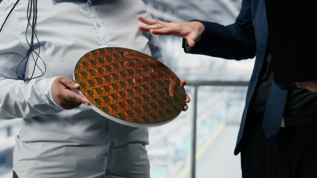 Workers in microchip smart factory reviewing semiconductor substrate design, optimizing photolithography. Teamworking industrial plant colleagues trialing silicon wafer materials, camera B close up