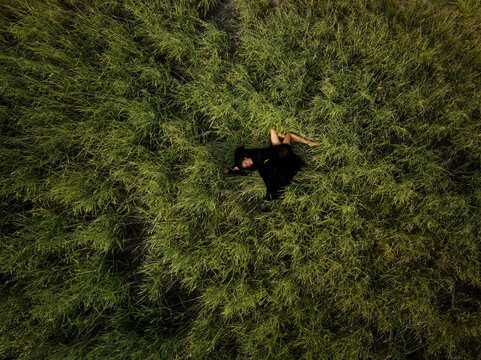Top Down View Woman in Black Dress Lying in Grass  Field