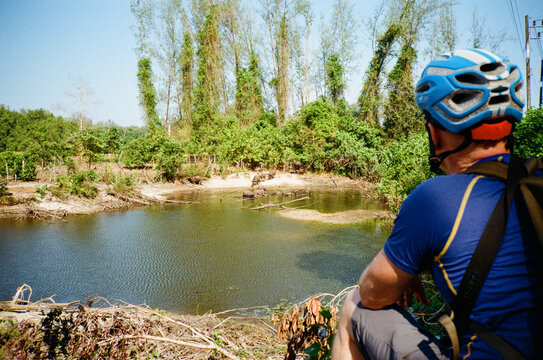 Cyclist looking at water buffalo in a pool, Thailand.