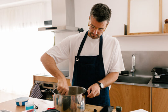 Man in an apron preparing a cake in his contemporary home