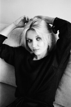 Blonde With Hands in Hair on Sofa, B&W Analog Film Portrait
