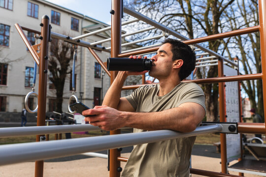 Athletic Man Drinking Water During Workout at Outdoor Park Gym