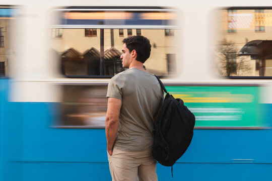 Man Standing by Speeding City Tram in Urban Setting