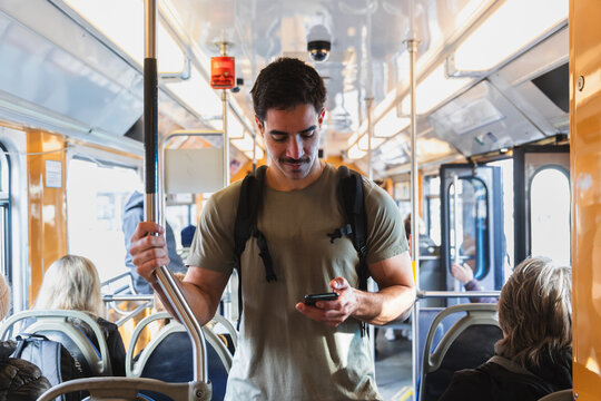Commuter Standing Inside a Moving Tram and Checking Smartphone