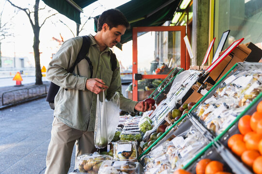 Young Man Picking Out Fresh Organic Mangoes at a Local shop