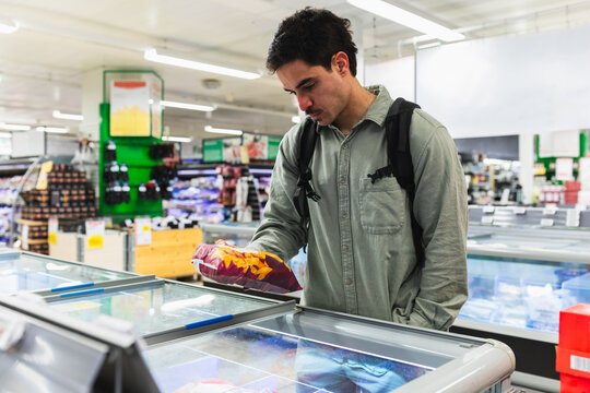 Man Checking Nutrition Label on Frozen Food Package in Supermarket