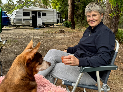 Woman Enjoys Drink With Dog at Campsite in Nature
