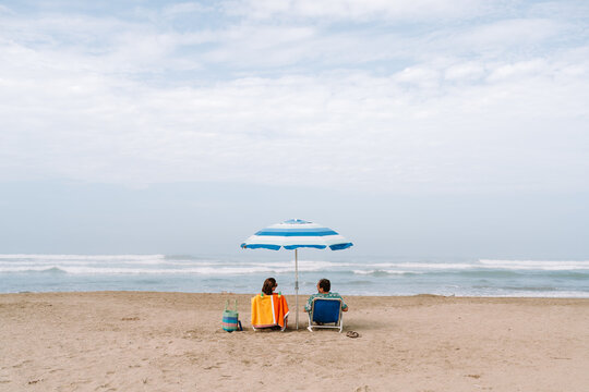 mature Couple Sitting Under Beach Umbrella  on Sunny summer Day
