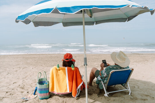 mature Couple Using Smartphones While Relaxing on Beach Chairs
