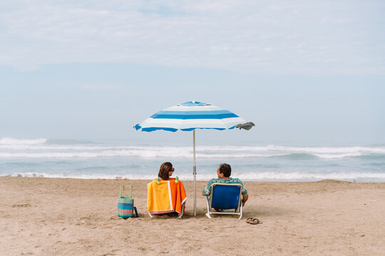 Couple Sitting Under Beach Umbrella  on Sunny summer Day
