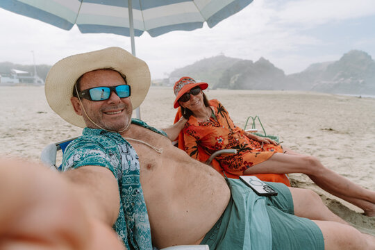 mature Couple Taking a Selfie While Relaxing on Beach 