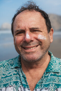 Portrait of Smiling Senior Man with Sunscreen on His Face at the beach
