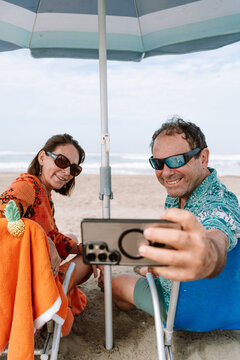 mature Couple Taking a Selfie with phone While Relaxing on Beach 