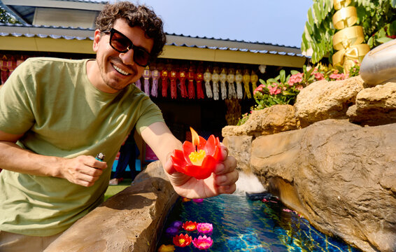 Man placing lotus candle in water in Chiang Rai Thailand