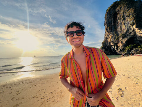 Man standing on sandy beach in Thailand at sunset
