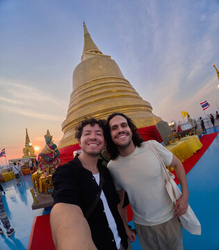 Two men posing near golden stupa in Bangkok Thailand