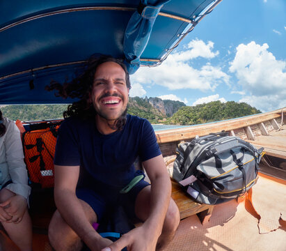 Man sitting on boat with backpack in Thailand