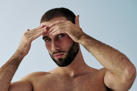 Man Touching His Forehead While Posing Against a Light Background