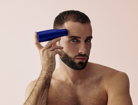 Man Uses Blue Bottle While Looking at the Camera Indoors